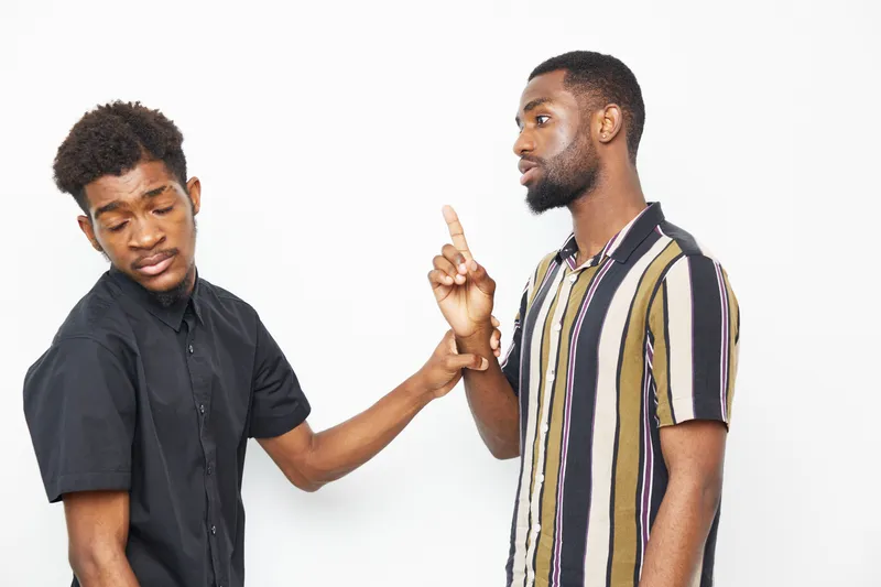 Two African American men engaged in conversation, one gesturing thoughtfully while the other listens attentively, showcasing a moment of connection and understanding.