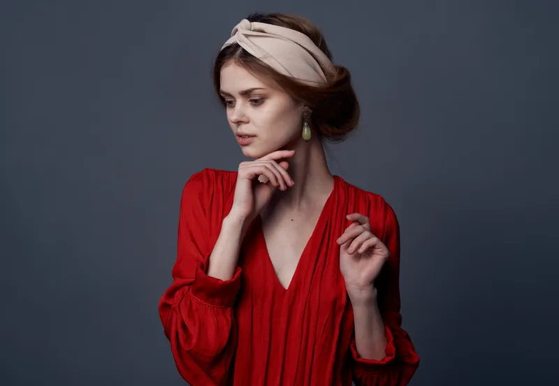 Элегантная женщина в красном платье с привлекательным взглядом на сером фоне