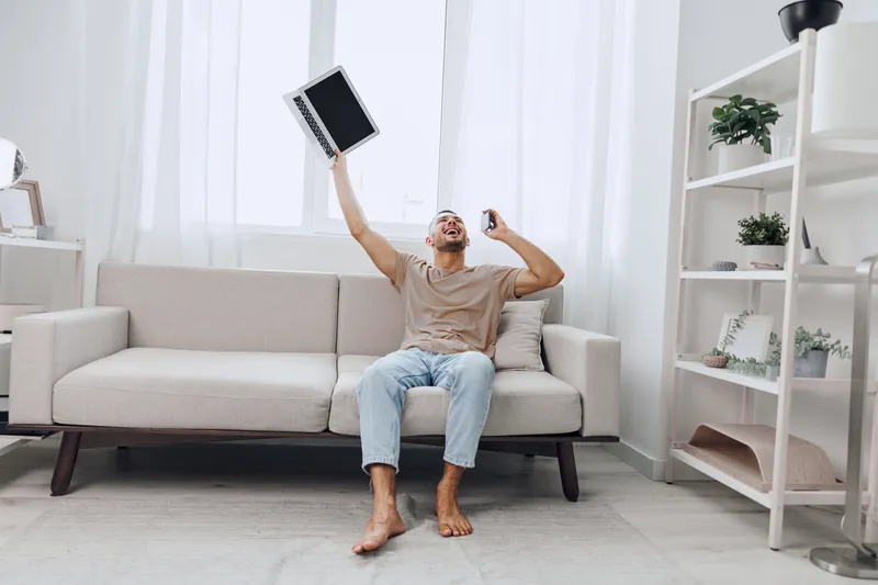 Excited man celebrating his successful side hustle, embracing emotional minimalism, home economy, and the joy of solo living while enjoying a digital detox.