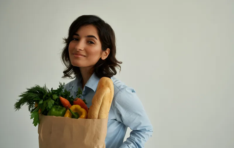 Веселая женщина с пакетом здоровой еды, свежие продукты