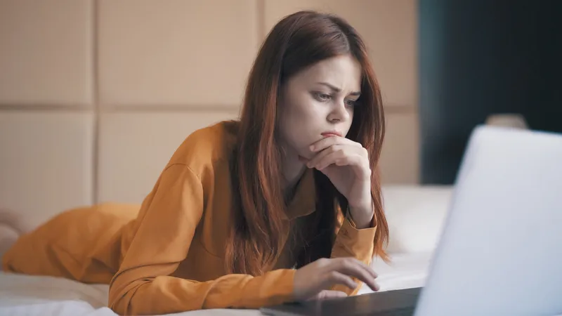 Симпатичная женщина лежит в спальне, работает в интернете как фрилансер
