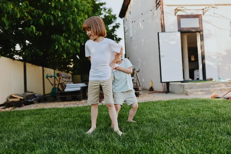 Two playful children, a boy and a girl, enjoy their time outdoors in a sunny garden, showcasing innocence and joy in their vibrant surroundings.