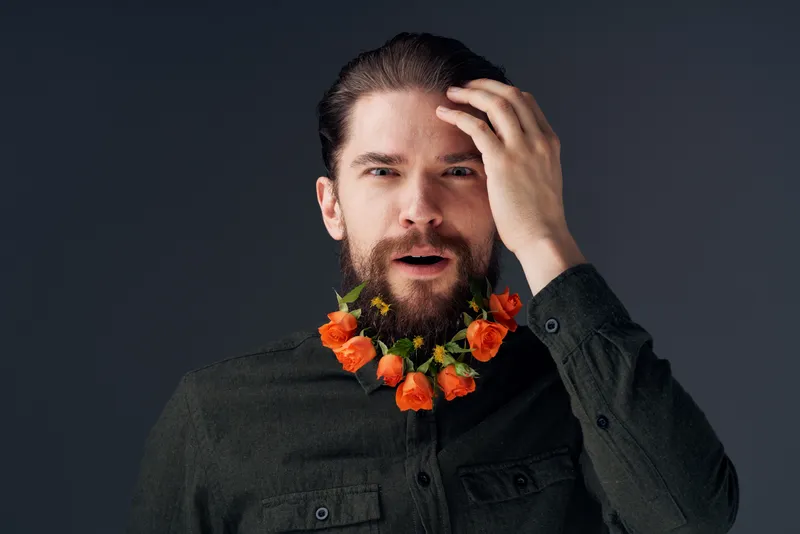 Портрет мужчины с цветами, вплетёнными в бороду, романтический подарок, эмоции крупным планом