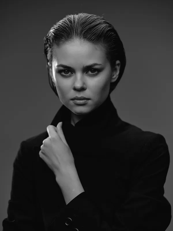 Black and white portrait of a serious woman with wet hair wearing a black turtleneck, showing intense emotion and elegance in studio lighting.