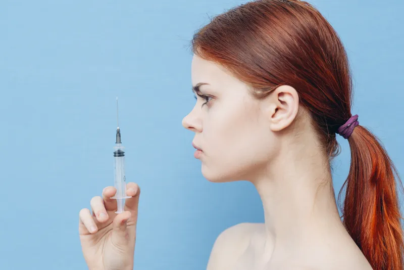 Женщина держит в руке шприц, инъекция ботокса, операция, изменение внешности