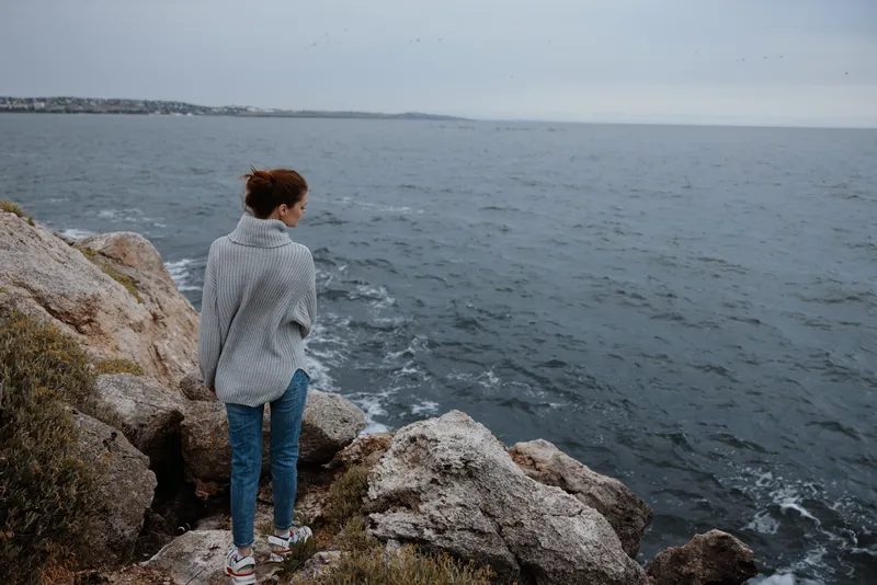 Женщина в свитере смотрит на облачное море, наслаждаясь природой