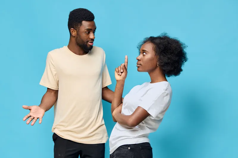 A couple engaged in a playful discussion, showcasing emotions and expressions of surprise and determination against a vibrant blue background