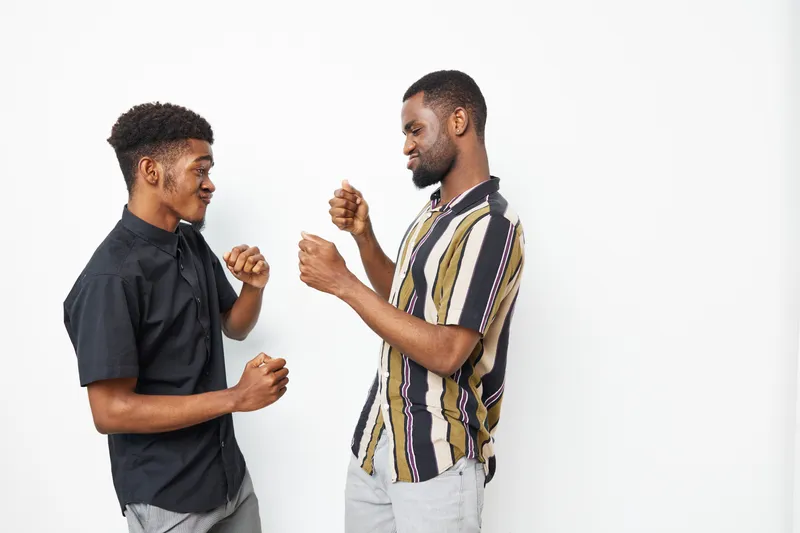 Two smiling African American men engaging in a joyful interaction, showcasing friendship and camaraderie in a playful atmosphere, perfect for social themes.