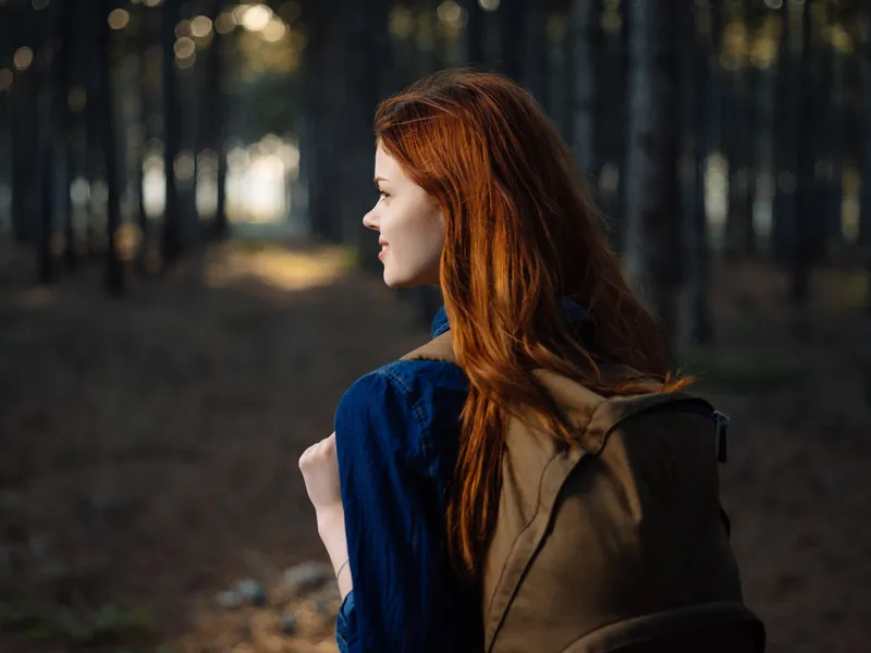 Рыжеволосая женщина с рюкзаком на природе в лесу, путешествие, образ жизни
