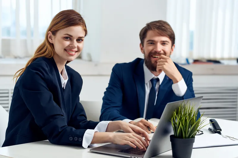 Коллеги работают вместе за ноутбуком в офисе