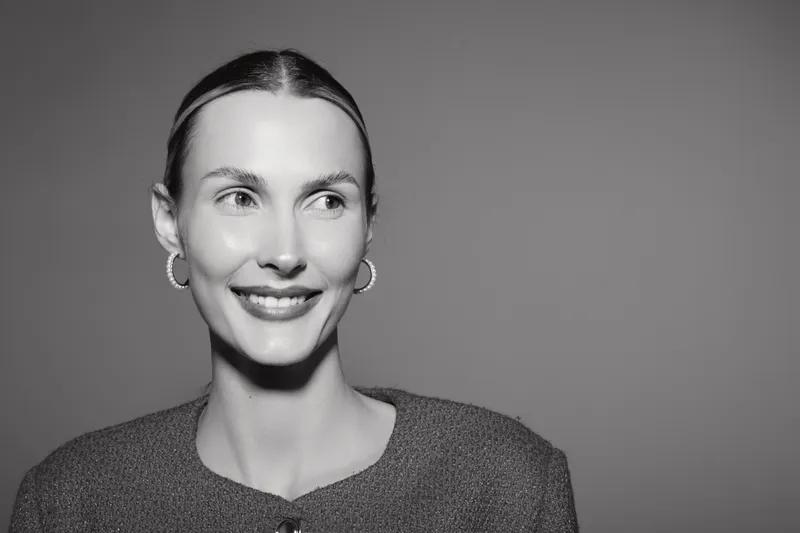 Portrait of a smiling Caucasian woman with fair skin wearing earrings and a textured jacket. Studio shot with soft lighting and neutral background. Concept for beauty and happiness.