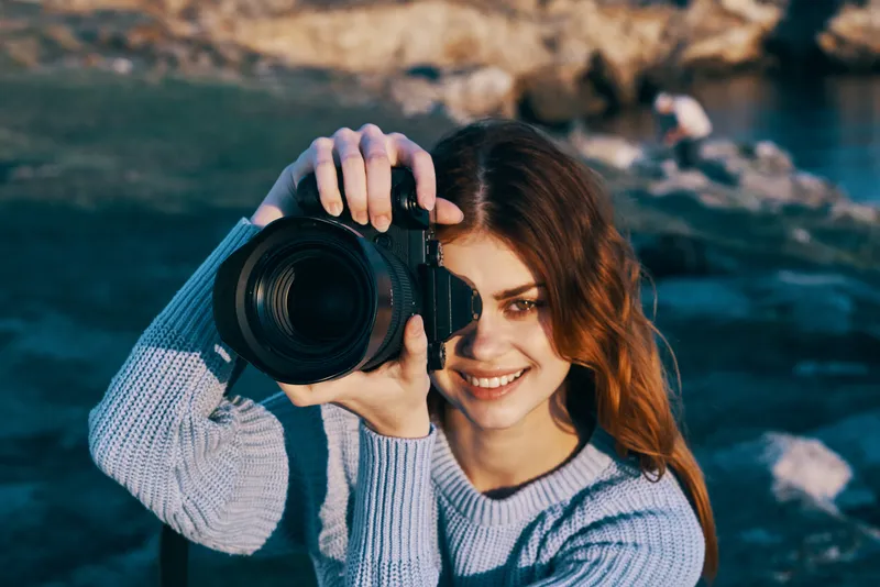 Жизнерадостная женщина-туристка с фотоаппаратом на природе, в горах, для профессионалов путешествий