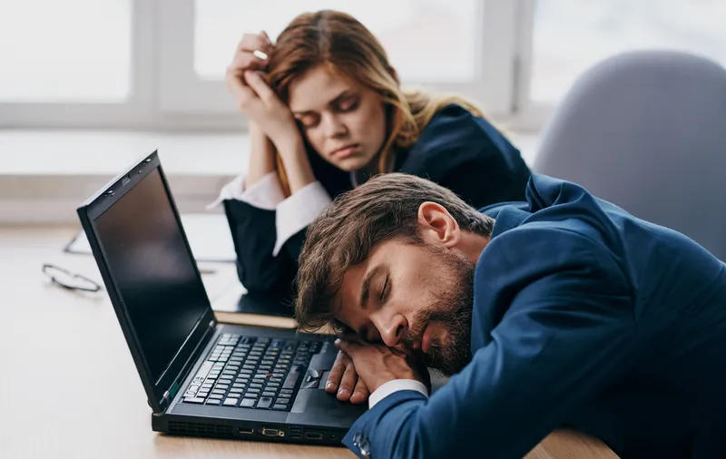 Коллеги по работе спят за столом перед ноутбуком, усталость, отдых
