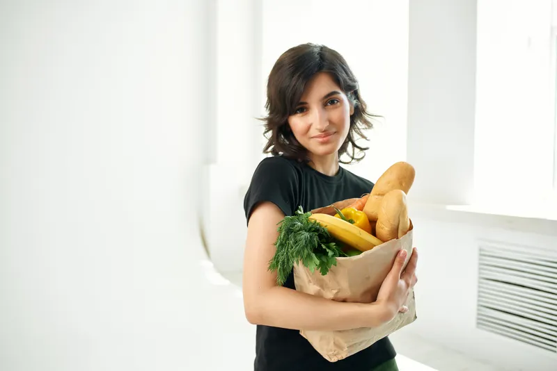 Брюнетка в черной футболке с пакетом продуктов