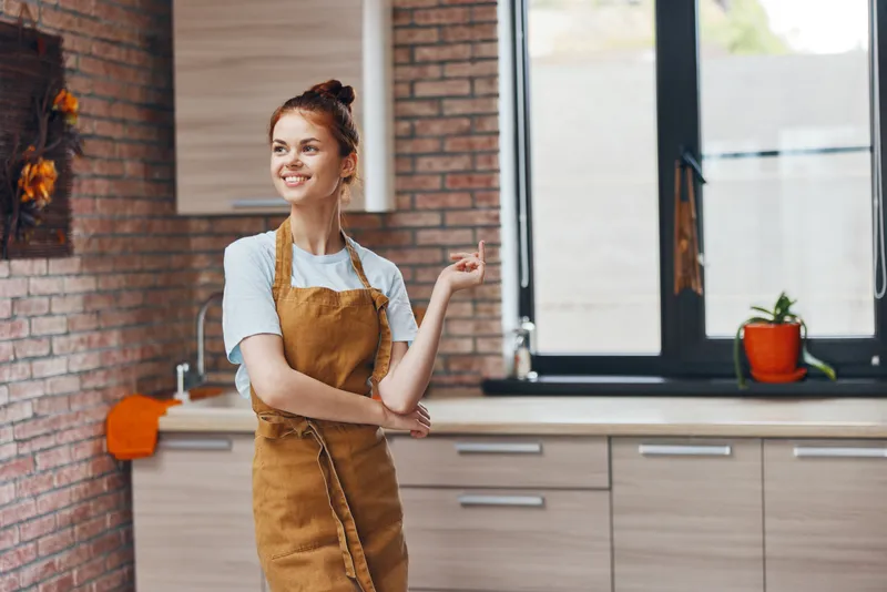 Симпатичная женщина в коричневом фартуке на кухне в современном стиле