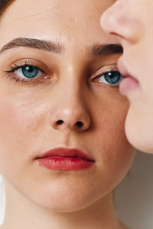 Closeup portrait of woman with blue eyes and red lips, smooth skin and natural makeup, in soft light with facial expression showing calm and focus. Beauty concept and skincare.