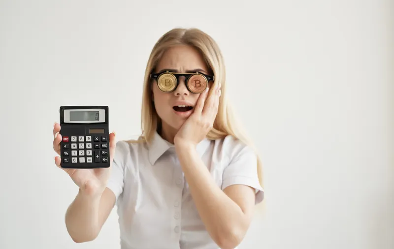 Весёлая женщина в очках в форме криптовалюты Bitcoin, калькулятор, финансы, деньги