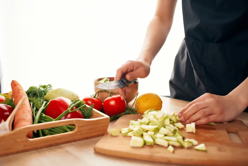 Крупный план нарезки овощей на разделочной доске на кухне, свежие продукты