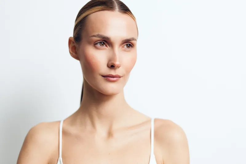 Woman skincare face cream portrait beauty wellbeing wellness studio soft closeup, calm female model, clean white background, natural light, skincare routine concept for wellbeing