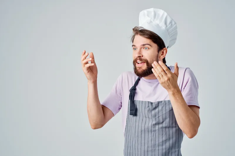 Мужчина в одежде повара на кухне занимается обработкой продуктов питания