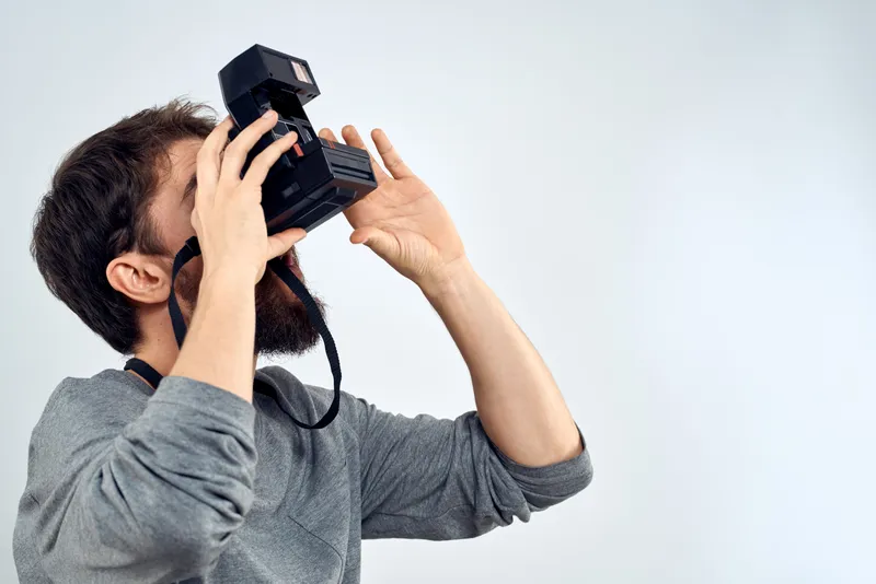 Фотограф-мужчина, профессиональная камера, работа, студия, технологии, современное искусство, светлый фон