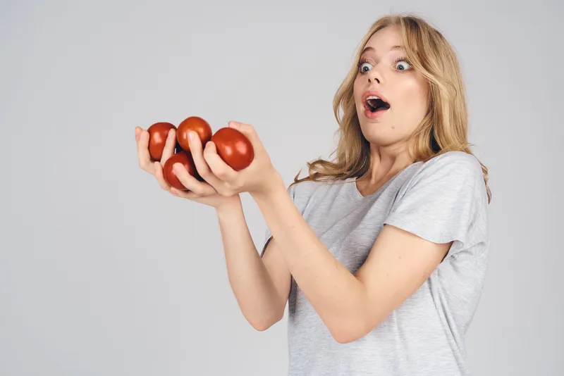 Эмоциональная женщина с продуктами в руках на сером фоне, еда, модель, кадр обрезан