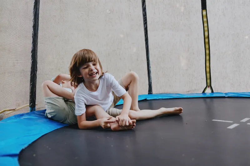 Happy boy playing joyfully on a trampoline with friends, showcasing fun and laughter in a vibrant outdoor setting, perfect for children's playtime themes.