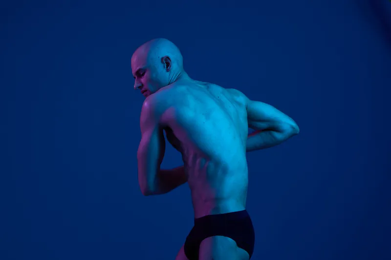 Athletic man showcasing strength in a captivating black and white image, highlighting his toned physique and dynamic pose, creating an impactful visual experience.