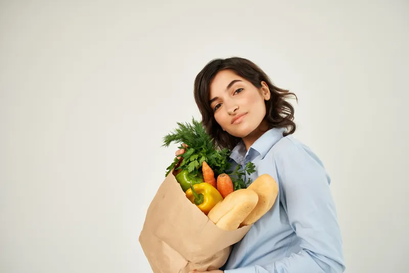 Брюнетка с пакетом продуктов из супермаркета: полезная еда, овощи