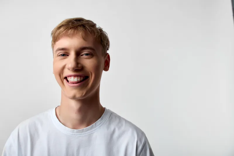 Smiling man wearing a plain white t shirt in a simple studio, conveying casual warmth, bright mood, friendly and approachable vibe suitable for lifestyle branding and positive messaging