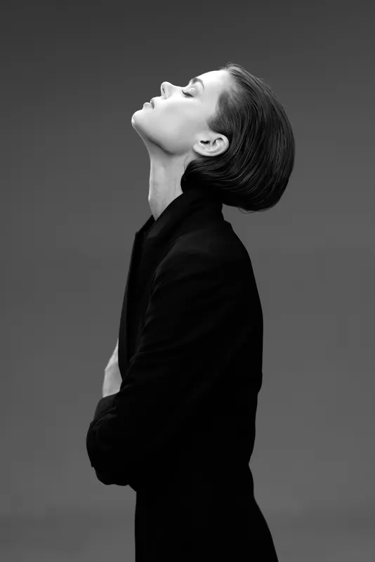 Elegant black and white portrait of a woman with eyes closed, wearing dark clothing, expressing calm and introspection.