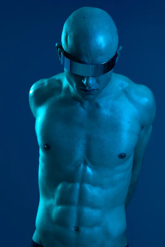 A striking image of a man with a muscular build, showcasing a futuristic look with metallic sunglasses. The cool blue lighting adds a unique and modern vibe.