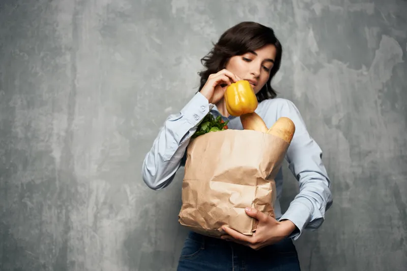 Женщина с пакетом продуктов в супермаркете, здоровая пища