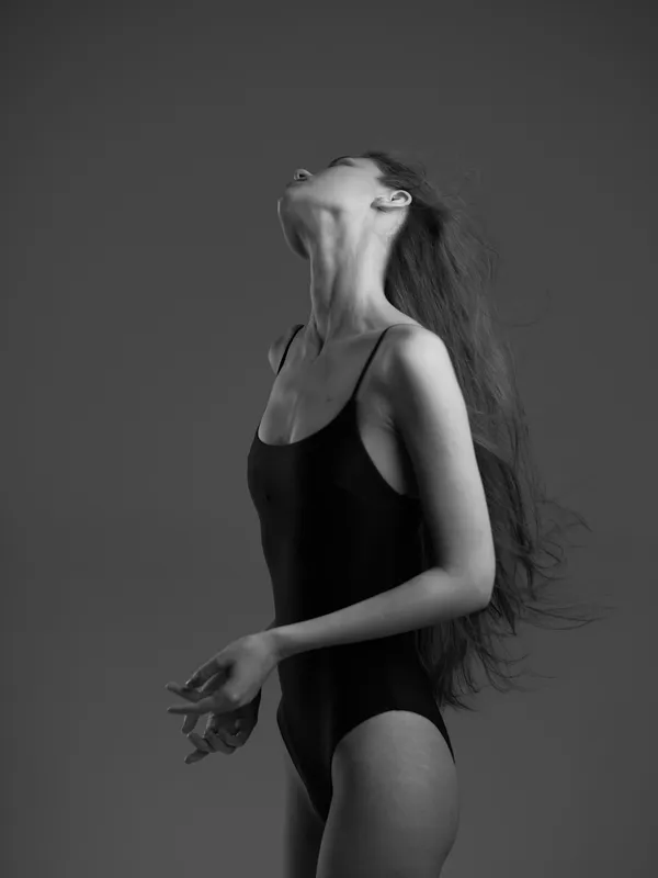 black and white woman posing in bodysuit with flowing hair, artistic and graceful expression