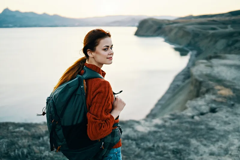 Женщина на отдыхе в горах на фоне заката и моря