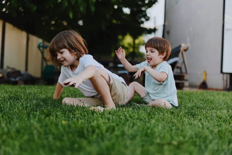 Playful children enjoying a sunny day in the garden, capturing the essence of childhood joy and laughter, surrounded by greenery and bright sunlight.