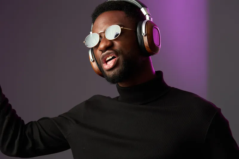Young man enjoying music with headphones, vibrant emotions, stylish outfit, urban background, modern lifestyle, expressive singing, and joyful vibe
