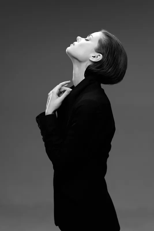 Black and white profile of a stylish woman in a dark jacket against a plain background, expressing elegance and calm.