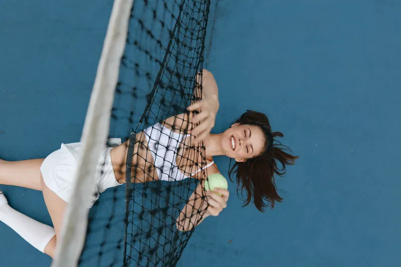 Happy female tennis player celebrating victory on the court, wearing sporty attire, with vibrant colors and dynamic background emphasizing the energy of sports and fitness