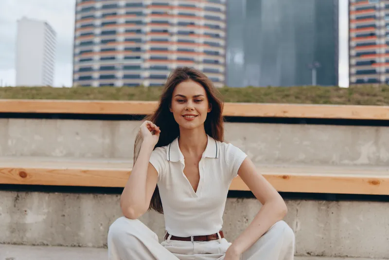 Confident woman in business attire smiling outdoors in a modern urban setting, embodying professionalism and elegance against an inspiring city backdrop.