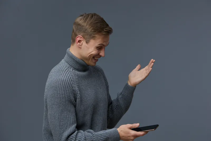 young smiling man wear grey turtleneck sweater hold smartphone look surprised modern technology digital detox concept isolated dark background