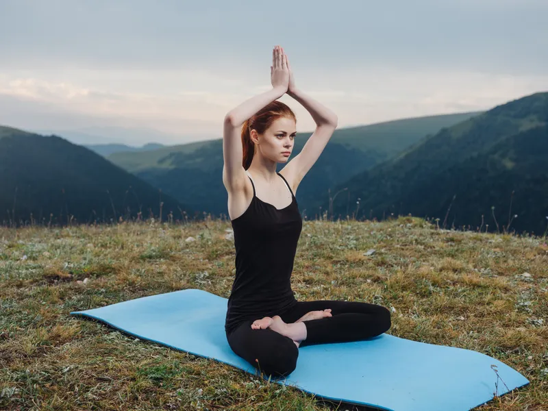 Спортивная женщина в горах занимается йогой и фитнесом на открытом воздухе