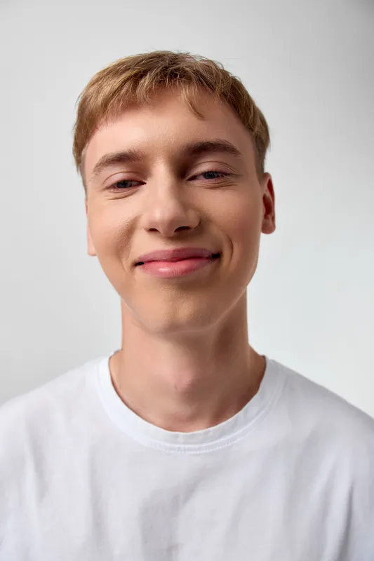 Smile, man, youth, casual, tshirt, front view, headshot in a bright studio with clean background, soft lighting, and confident expression suitable for lifestyle and personal growth themes
