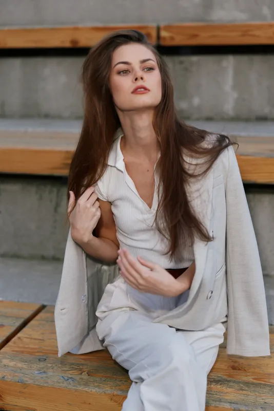 Businesswoman in stylish attire, showcasing confidence and elegance in a modern urban environment with soft colors and natural lighting.