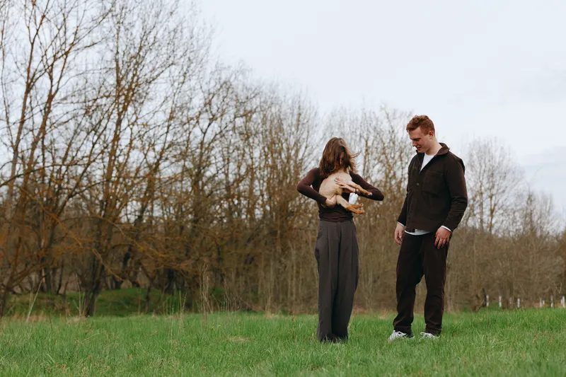 Casual couple outdoors, playful dancing in a sunlit field, relaxed posture, gentle breeze, natural colors, lush greenery, warm connection, candid lifestyle moment, bright and airy atmosphere