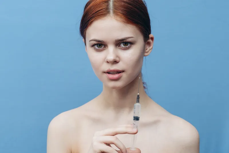 Женщина со шприцем, обнаженные плечи, омолаживающая инъекция