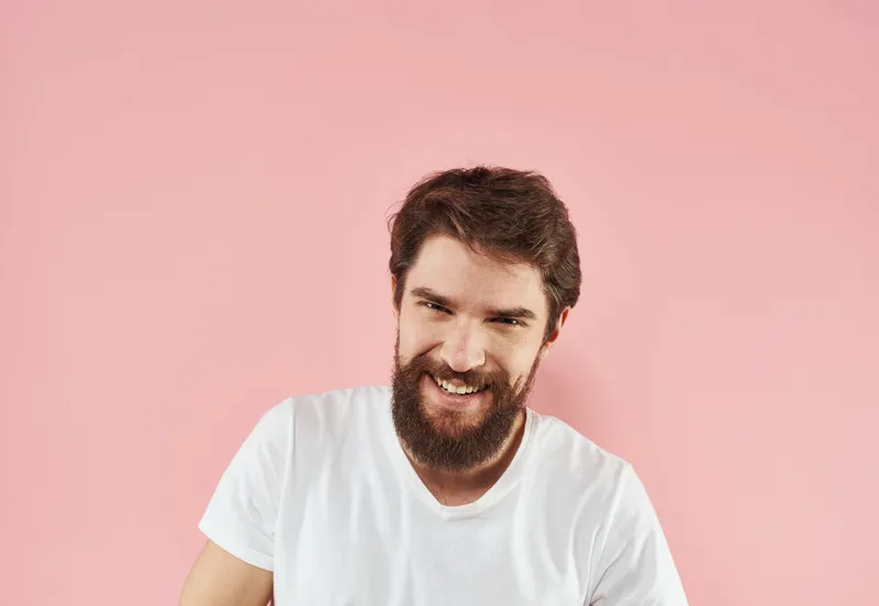 Крупный план портрета мужчины в белой футболке на розовом фоне