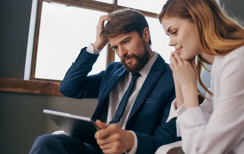Деловой мужчина и женщина, коллеги по работе, используют планшет и современные технологии в профессиональной деятельности