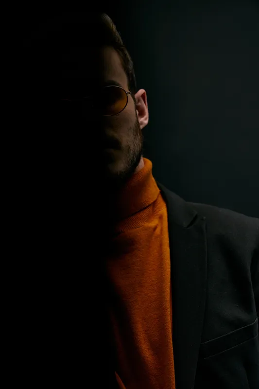 Силуэт мужчины в свитере и куртке на черном фоне, падающая тень