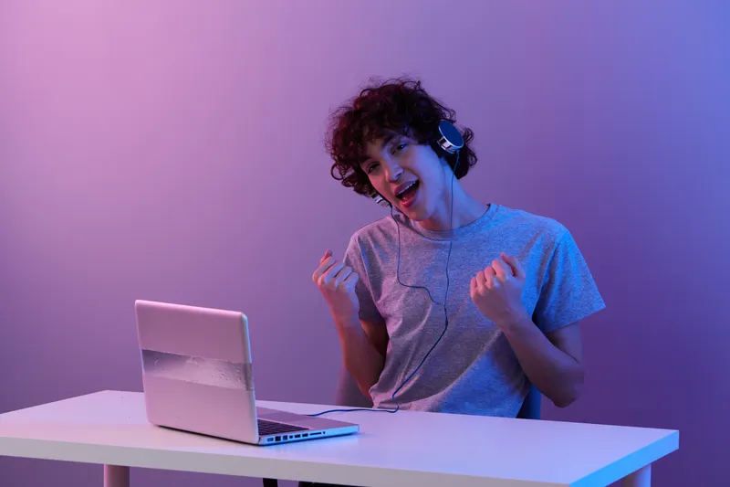 Мужчина сидит за столом с игровым ноутбуком на изолированном фоне